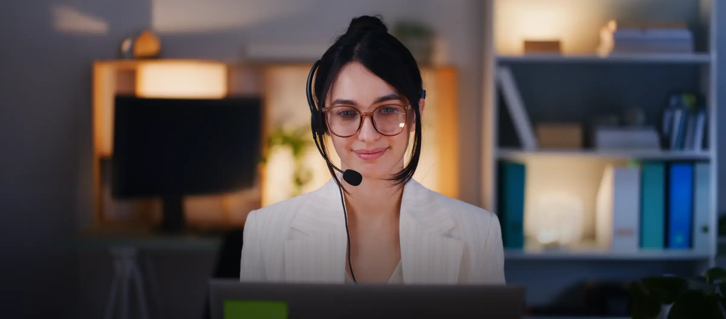 An admissions counselor wearing a headset, smiling at her screen
