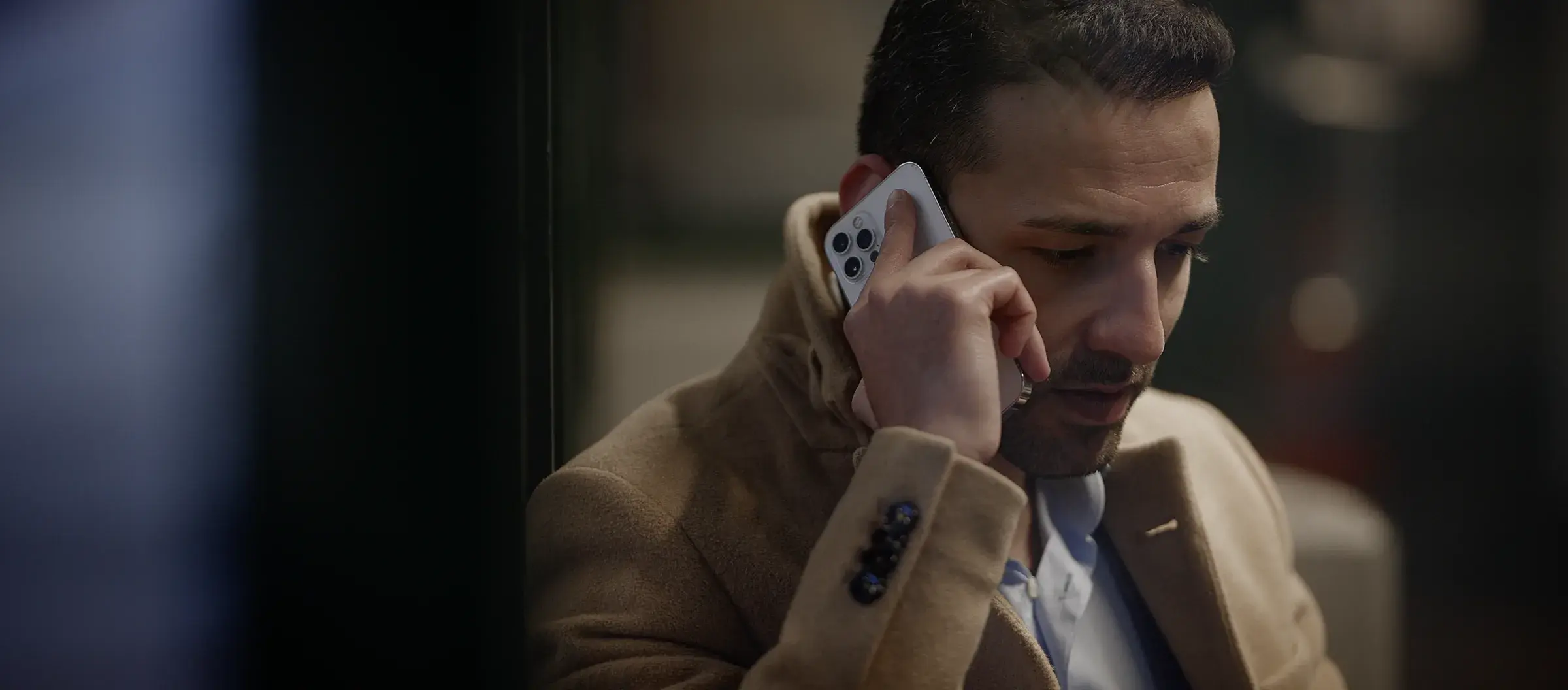 A man on a phone call in a coat, looking down