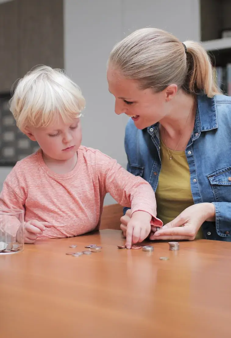 A mother and her young son counting coins at a table