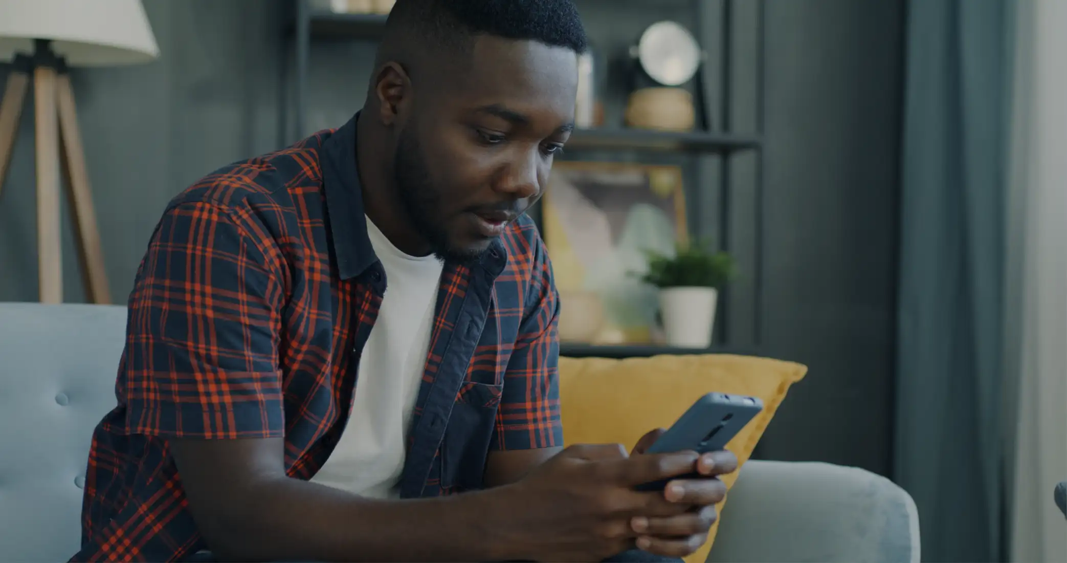A man on a sofa smiling at his phone