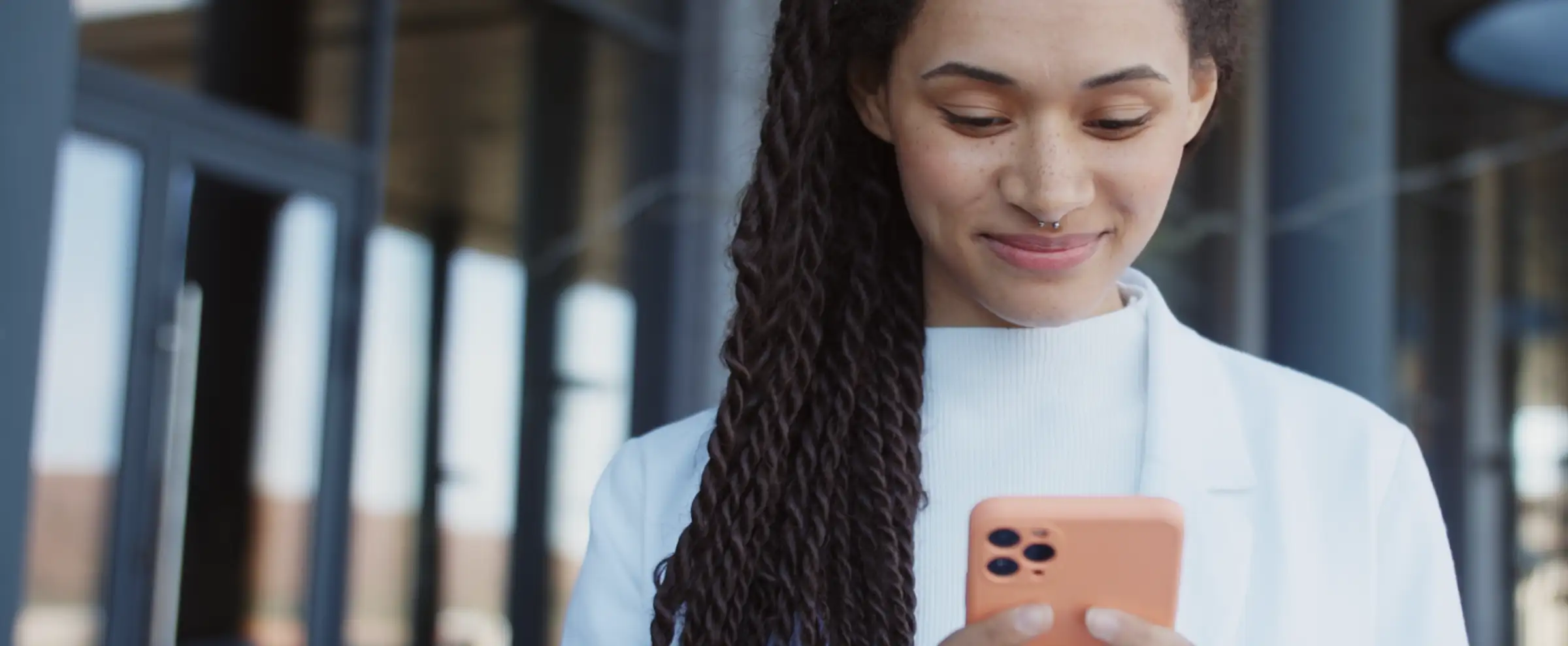 A woman outside smiling at her phone