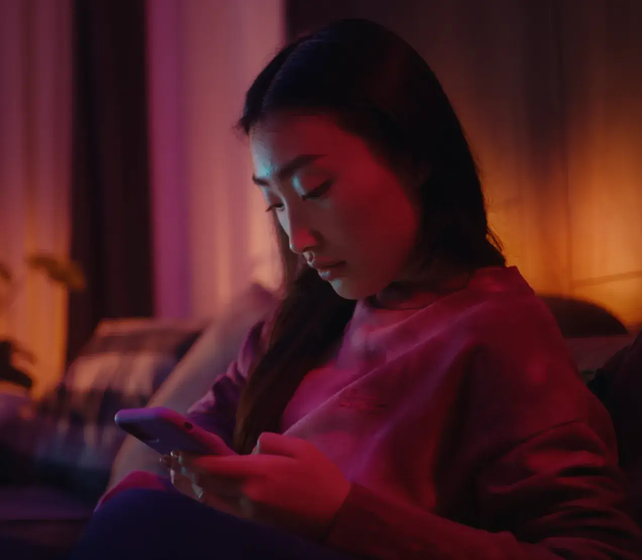 A young woman looking at her phone at night